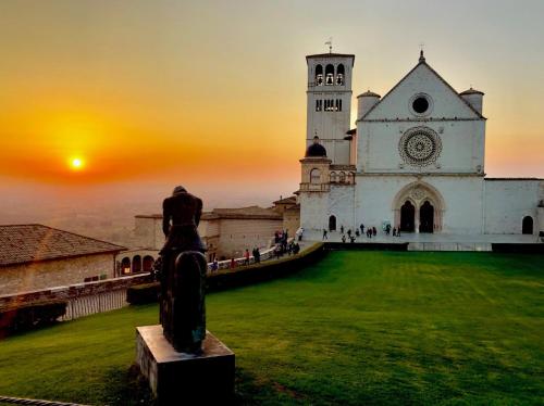 a church with a statue in front of it at sunset at B&B La Fisarmonica in Bastia Umbra