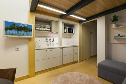 a kitchen with white cabinets and a tv on the wall at Hiport Apart Hotel in Dnipro