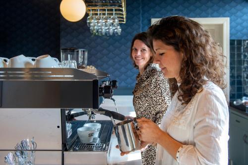 - deux femmes debout dans une cuisine équipée d'une machine à café dans l'établissement Boutique Hotel Het Scheepshuys, à Breda