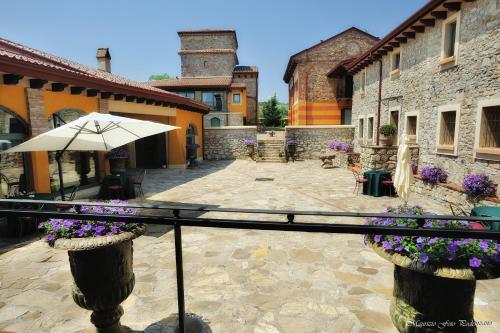 an outdoor patio with an umbrella and some buildings at Relais La Colombara Spa & Wellness in Travo