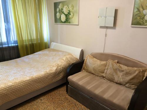 a bedroom with a bed and a couch and a window at Nice Flats Noviy Arbat in Moscow