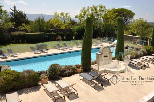 une piscine avec des chaises longues et des arbres dans l'établissement Domaine Les Bastidons, à Gordes