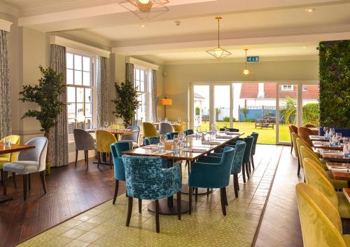 a dining room with tables and chairs and windows at Kingscliff, BW Signature Collection in Clacton-on-Sea