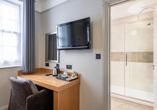 a room with a desk with a television on the wall at Kingscliff, BW Signature Collection in Clacton-on-Sea
