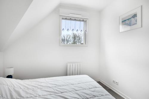 une chambre blanche avec un lit et une fenêtre dans l'établissement Escapade en duo au coeur de Sarzeau, à Sarzeau