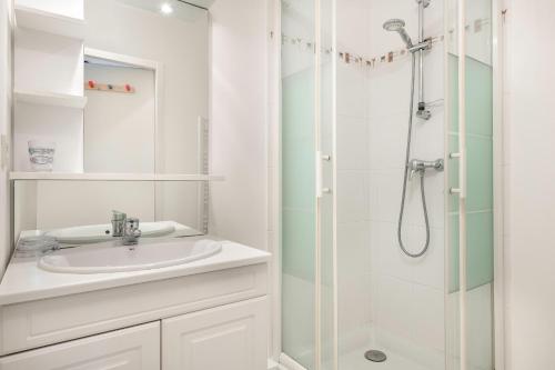une salle de bain blanche avec un lavabo et une douche dans l'établissement Escapade en duo au coeur de Sarzeau, à Sarzeau