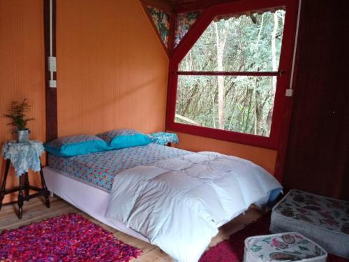 ein Schlafzimmer mit einem Bett in einem Zimmer mit einem Fenster in der Unterkunft Vila do Mago in Itamonte