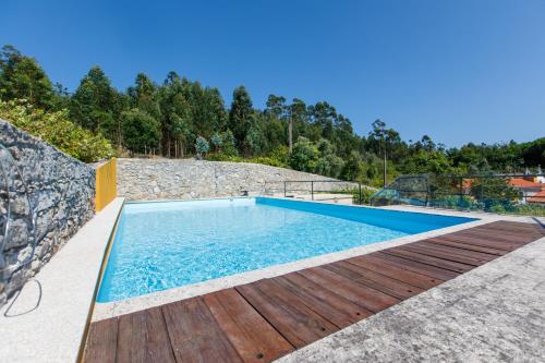 a swimming pool with a wooden deck next to a rock wall at Quinta dos Fangueiros in Riba de Âncora