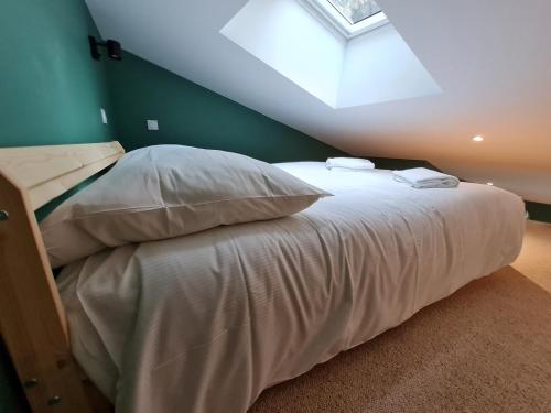a bedroom with a bed with white sheets and a skylight at La Canopée in Riom