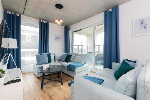 uma sala de estar com cortinas azuis e um sofá em Lux Family Apartment Nadmorskie Tarasy by Renters em Gdynia