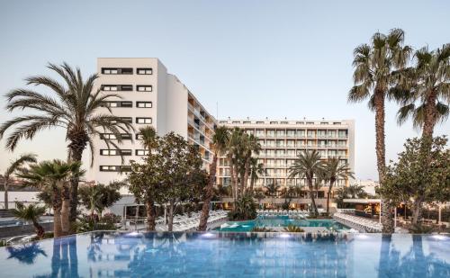 une image d'un hôtel avec une piscine et des palmiers dans l'établissement AQUA Hotel Silhouette & Spa - Adults Only, à Malgrat de Mar