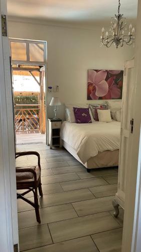 a bedroom with a bed and a chair and a chandelier at Victorian Beach Cottages in Amanzimtoti