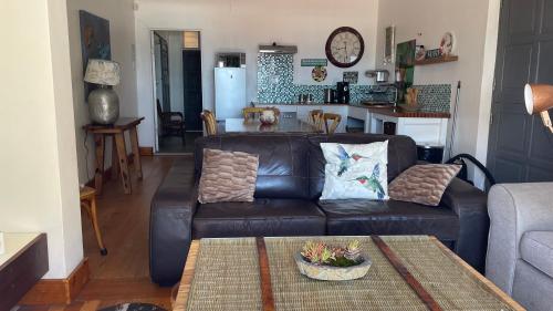 a living room with a leather couch and a table at Victorian Beach Cottages in Amanzimtoti
