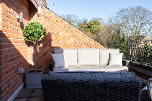 a white couch sitting on a brick wall at Tiger Roof Terrace Lymm in Lymm
