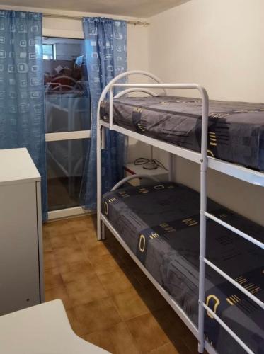 two bunk beds in a room with blue curtains at Appartamento Torre 82 in Torre Dei Corsari