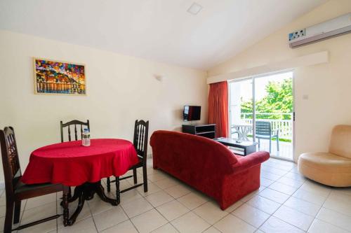 a living room with a red table and a chair at Siesta Hotel in Morne Rouge