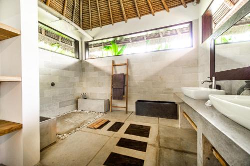 a bathroom with a sink and a tub and a mirror at Villa Jac in Selong Belanak