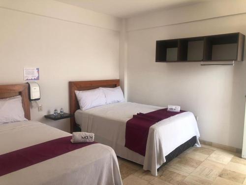a bedroom with two beds and a tv on the wall at Motel Moon in Puebla