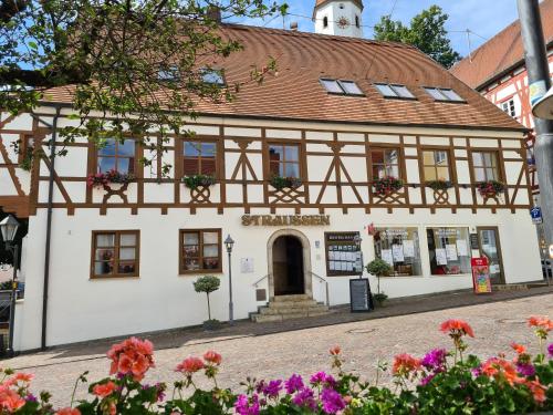 a building in a town with flowers in front at Hotel-Restaurant Straussen in Harburg