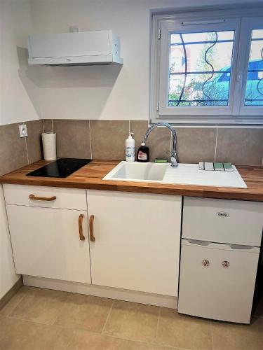 a kitchen with white cabinets and a sink and a window at Studio Le Plum'Art, 10mn Zoo de Beauval avec jardin in Noyers-sur-Cher