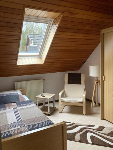 a bedroom with a bed and a window and a chair at Ferienwohnung Hartmann in Wehdel