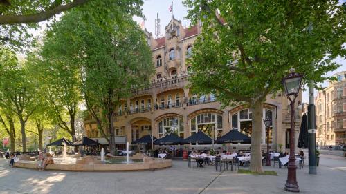 a building with people sitting at tables in front of it at Clayton Hotel Amsterdam American in Amsterdam