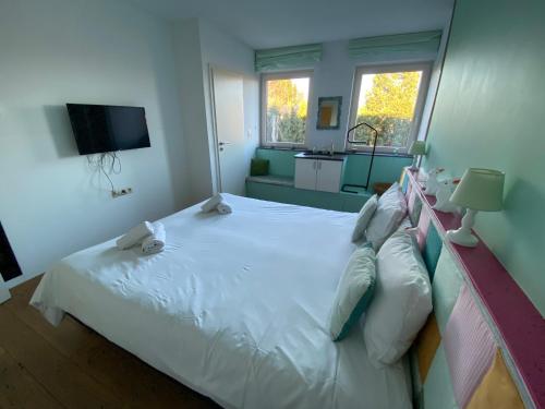 a bedroom with a white bed and a television at Maison Jules in Sainte-Ode