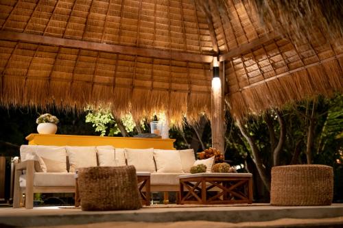 a white couch sitting under a straw umbrella at Club Mango Resort in Kalpitiya