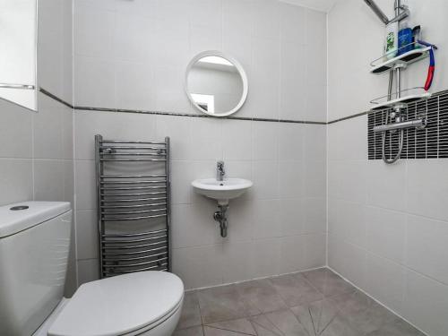 a white bathroom with a toilet and a sink at Specious 3bed property with parking & large garden in Aveley