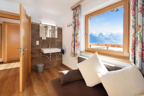 a bathroom with a couch and a sink and a window at Fewo Innerspielleiten 24 Personen in Hippach