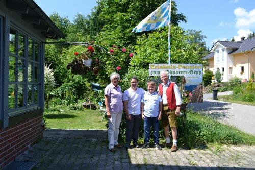 a family poses for a picture in front of a building at Erlebnispension Zum Wanderer Sepp in Arnbruck