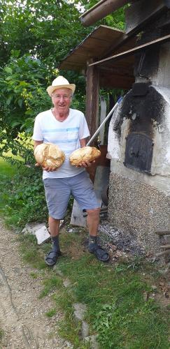 a man holding some bread in front of an oven at Erlebnispension Zum Wanderer Sepp in Arnbruck