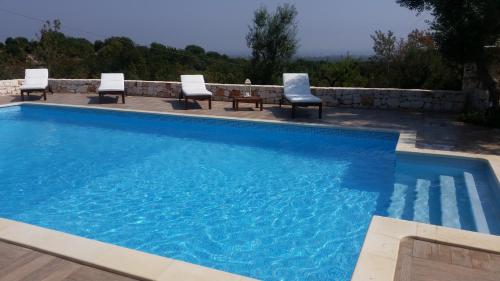 a swimming pool with four chairs and a table at Villa Mest Pepp in Monopoli