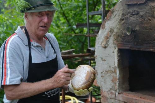 a man in an apron holding a loaf of bread at Erlebnispension Zum Wanderer Sepp in Arnbruck