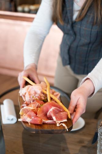 a person holding a plate of meat and french fries at Hôtel VoulezVous by Les Etincelles in Tignes