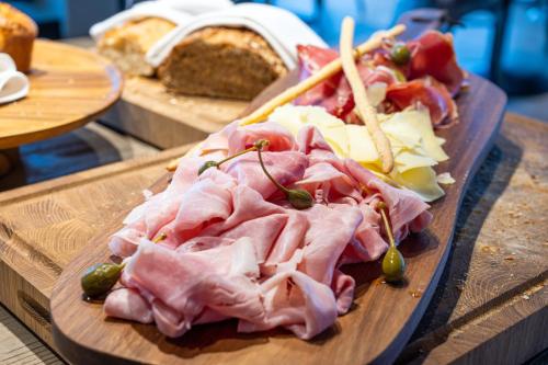 a cutting board with ham and cheese and other foods at Hôtel VoulezVous by Les Etincelles in Tignes