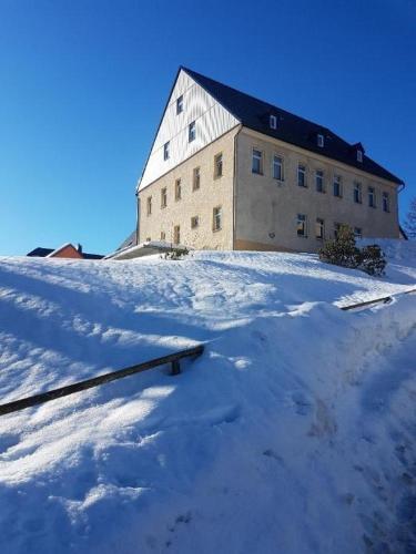 a large building on top of a snow covered hill at Die Alte Bäckerei in Jöhstadt