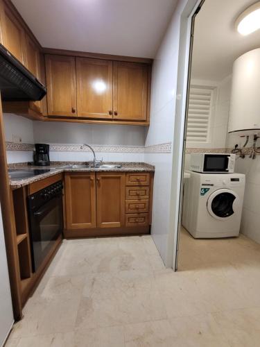 a kitchen with wooden cabinets and a washer and dryer at Gemelos 22-Fincas Benidorm in Benidorm