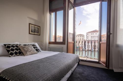 a bedroom with a bed and a large window at Design Apartment with Balcony on the Grand Canal R&R in Venice