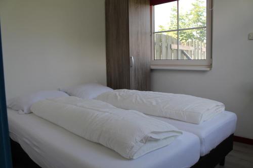 two pillows on a bed in a room with a window at boerderij de duinen 111 in De Cocksdorp