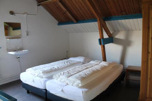 two beds in a room with wooden ceilings at boerderij de duinen 111 in De Cocksdorp