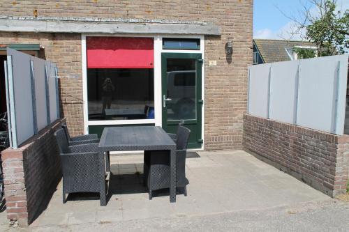 a black table and chairs in front of a building at boerderij de duinen 111 in De Cocksdorp