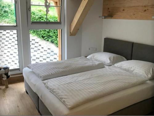 two beds in a room with two windows at Penthouse Alpendorf in Sankt Johann im Pongau