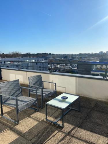 a patio with two chairs and a table on a roof at La Résidence Amal in Talence