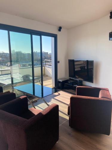 a living room with two couches and a tv at La Résidence Amal in Talence