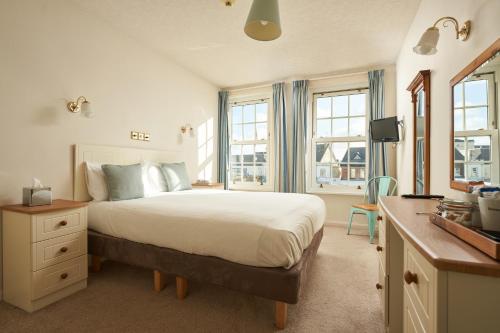 a bedroom with a bed and a desk and windows at Great Western in Newquay