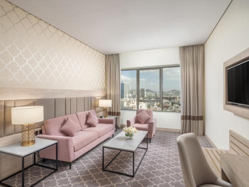 ein Wohnzimmer mit rosa Möbeln und einem großen Fenster in der Unterkunft Wirgan Hotel Al Azizyah in Mekka
