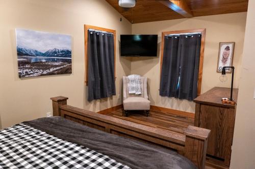 Schlafzimmer mit einem Bett, einem TV und einem Stuhl in der Unterkunft NEW!! House Near Raystown Lake in Peaceful Wooded Area in Huntingdon