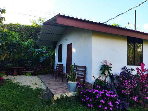 a small white house with a wooden porch and flowers at Bijagua paradise Río Celeste in Bijagua