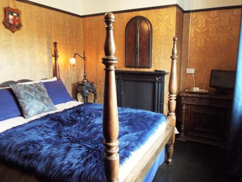 um quarto com uma cama com um cobertor azul em Old Vicarage B&B em Coleford